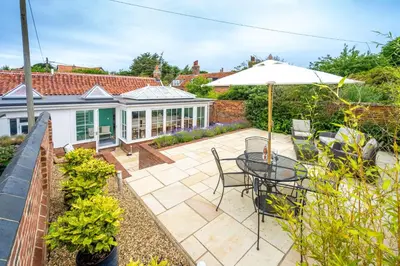 a patio with a table and chairs and an umbrella at Myrtle Cottage 4 in Friston