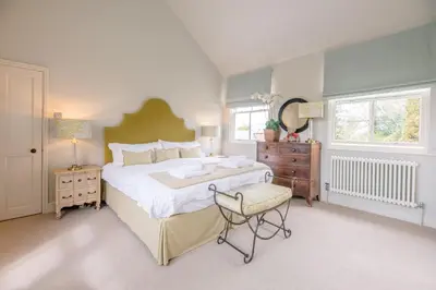 a bedroom with a large bed and a chair at Little Fig in Aldeburgh