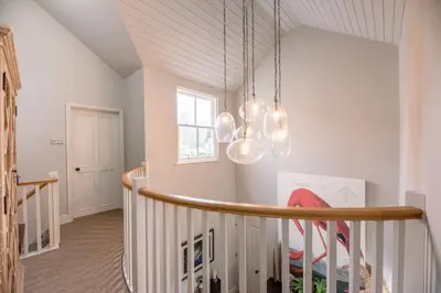 a room with a staircase with a chandelier at Little Fig in Aldeburgh
