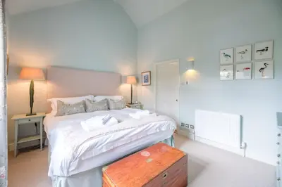 a bedroom with a large white bed with a wooden table at Little Fig in Aldeburgh