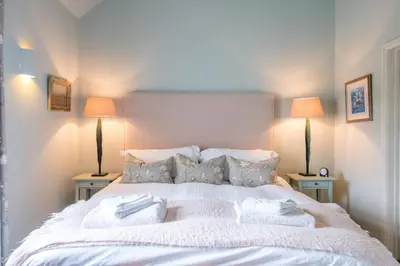 a bedroom with a large white bed with two lamps at Little Fig in Aldeburgh