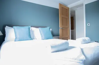 a bedroom with a large white bed with blue walls at Stylish 3x bed house in Soham in Soham
