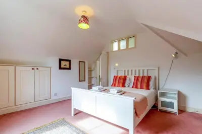 a bedroom with a white bed with red pillows at Pass the Keys Spacious Victorian Home with Free Parking in Cambridge