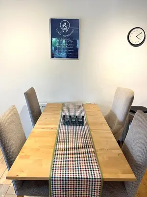 a wooden table with chairs and a clock on the wall at Casa di Qeis a double bedroom ground floor flat with free parking in Chesterton