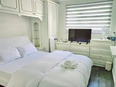 a white bedroom with a bed and a flat screen tv at Jays-Rooms in Pitsea