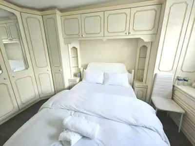 a bedroom with a large white bed with towels on it at Jays-Rooms in Pitsea