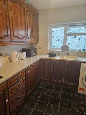 a kitchen with wooden cabinets and a sink and a window at Jays-Rooms in Pitsea