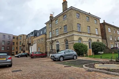 a large brick building with cars parked in a parking lot at Chelmsford City Central Ground Floor Apartment Next To Town Centre in Chelmsford