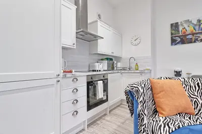 a kitchen with white cabinets and a zebra print chair at Chelmsford City Central Ground Floor Apartment Next To Town Centre in Chelmsford