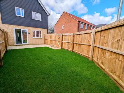 a backyard with a wooden fence and green grass at 3-Bed, Sleeps 6, 3 Bath, Parking, WiFi in Watton