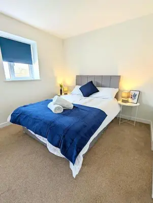 a bedroom with a large bed with a blue blanket at 3-Bed, Sleeps 6, 3 Bath, Parking, WiFi in Watton