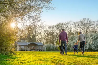 a family walking through a field with a house in the background at Cuckoo - Sweffling Hall in Rendham