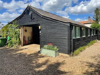 a black shed with a door and a plant in a pot at 2 Bed Barn - Sleeps 4 - Pets - Parking - Wifi in Downham Market