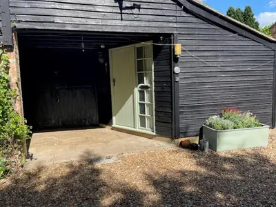 a black shed with a door and a patio at 2 Bed Barn - Sleeps 4 - Pets - Parking - Wifi in Downham Market