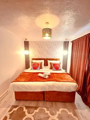 a bedroom with a large bed and a chandelier at Luxe Smart Home - Basildon Serviced Accommodation - 7 Mins Walk To Basildon Town Centre, Hospital & Train Station in Basildon