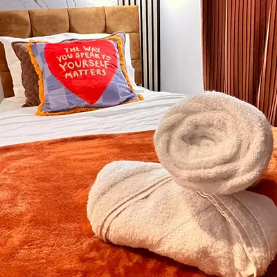 a bed with a pillow with a towel on it at Luxe Smart Home - Basildon Serviced Accommodation - 7 Mins Walk To Basildon Town Centre, Hospital & Train Station in Basildon