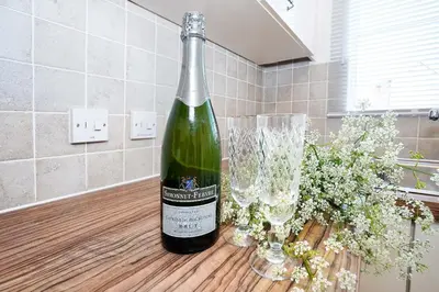 a bottle of wine sitting on a table with a glass at Yew Tree Close Mildenhall Bury St Edmunds in Mildenhall