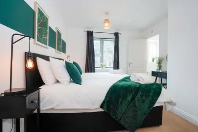 a bedroom with a large bed with a green blanket at Yew Tree Close Mildenhall Bury St Edmunds in Mildenhall