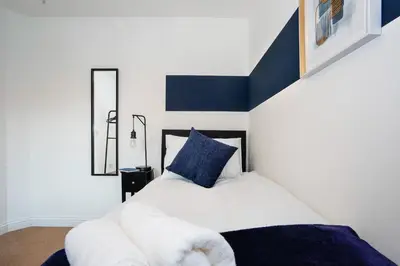 a bedroom with a white bed with a blue pillow at Yew Tree Close Mildenhall Bury St Edmunds in Mildenhall