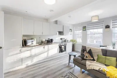 a kitchen and living room with white cabinets and a couch at Ipswich Town center Gem Sleep 5 in Ipswich