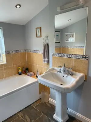 a bathroom with a sink and a tub and a mirror at The Grange in Attleborough