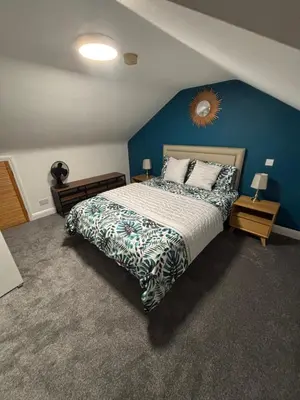 a bedroom with a large bed with a blue wall at The Grange in Attleborough