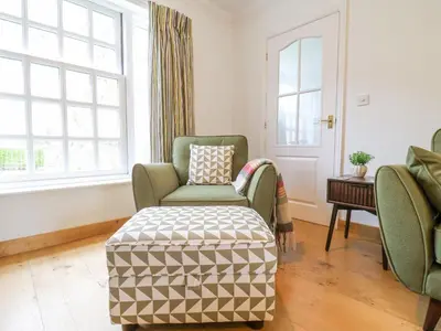 a living room with a chair and a ottoman at 23 Church Farm Lane in Halesworth