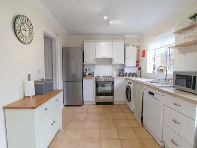 a kitchen with white cabinets and stainless steel appliances at 23 Church Farm Lane in Halesworth