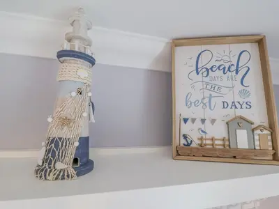 a bottle on a shelf next to a picture of a lighthouse at 23 Church Farm Lane in Halesworth