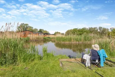 a person sitting in a chair next to a lake at 2 Bed in Welney oc-k29369 in Welney