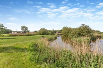 a river with tall grass next to a field at 2 Bed in Welney oc-k29369 in Welney