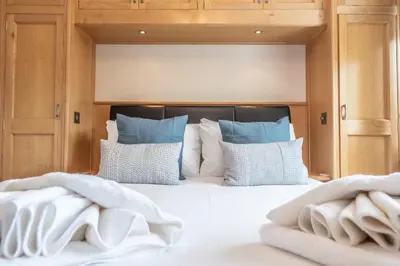 a bed with white sheets and blue pillows at 5 Toller Close, Orford in Orford