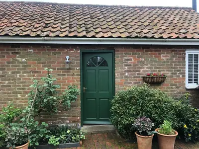a green door on a brick house with potted plants at The studio spring house in Alderton