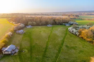 an overhead view of a large grass field with houses at Linnet - Sweffling Hall in Rendham