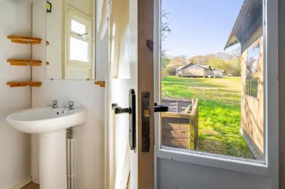 a bathroom with a sink and a door with a window at Swallow - Sweffling Hall in Rendham