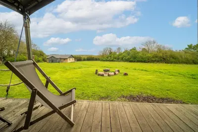 a chair sitting on a porch with a large field at Sweffling at Lantern and Larks in Rendham