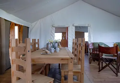 a wooden table and chairs in a tent at Swift - Sweffling Hall in Rendham