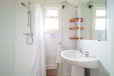 a white bathroom with a sink and a mirror at Swift - Sweffling Hall in Rendham