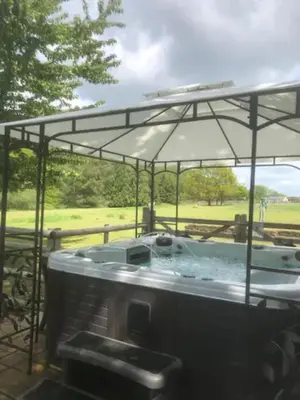 a hot tub with an umbrella on top of it at The Willows in Great Horkesley