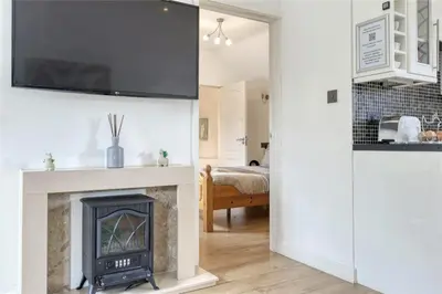 a living room with a fireplace with a tv above it at The Willows in Great Horkesley