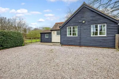 a black house with a driveway in front of it at The Willows in Great Horkesley