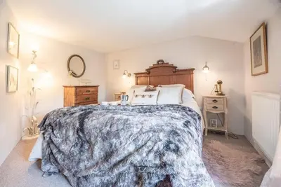 a bedroom with a large bed with a wooden headboard at 2 Fox Cottage, Darsham in Darsham