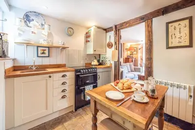 a kitchen with white cabinets and a wooden table at 2 Fox Cottage, Darsham in Darsham