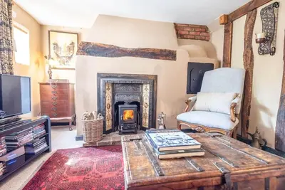 a living room with a fireplace and a chair at 2 Fox Cottage, Darsham in Darsham
