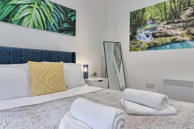 a bedroom with a bed and a painting on the wall at Chelmsford City Centre Modern Duplex With Parking, Wi-Fi & Netflix in Chelmsford