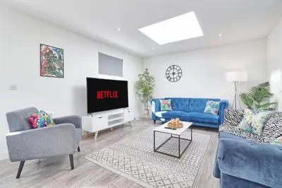 a living room with blue furniture and a tv at Chelmsford City Centre Modern Duplex With Parking, Wi-Fi & Netflix in Chelmsford