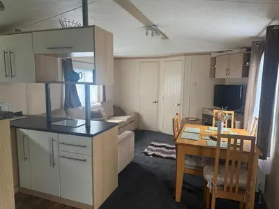 a small kitchen and dining room with a table and a room at 6 Bed Static Carvan Seawick Holiday Park in Saint Osyth