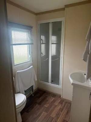a bathroom with a shower and a toilet and a sink at 6 Bed Static Carvan Seawick Holiday Park in Saint Osyth