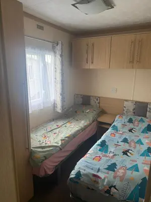 a small room with two beds and a window at 6 Bed Static Carvan Seawick Holiday Park in Saint Osyth