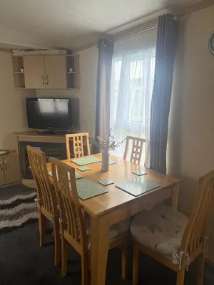 a dining room with a wooden table and chairs at 6 Bed Static Carvan Seawick Holiday Park in Saint Osyth
